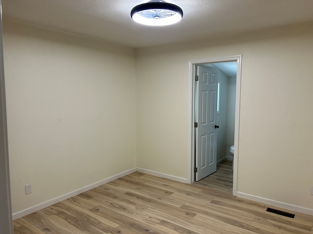 empty room featuring visible vents, baseboards, and light wood finished floors