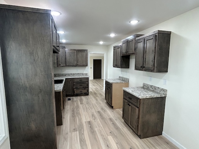 kitchen with baseboards, dark brown cabinetry, light wood-style flooring, and light countertops