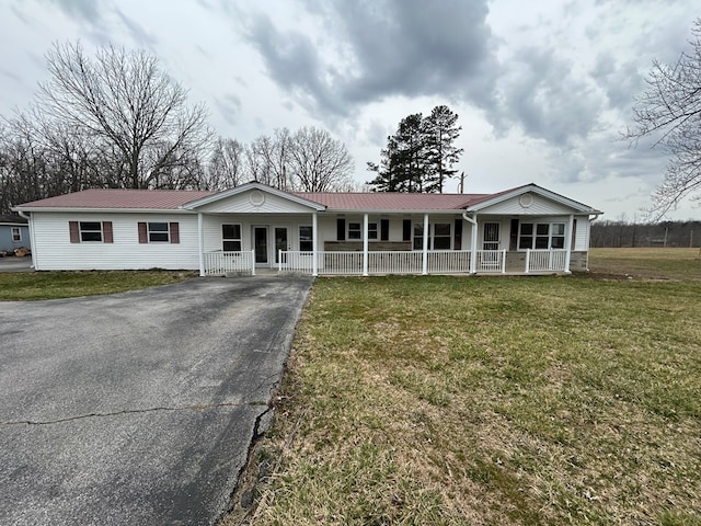 ranch-style home with metal roof, driveway, covered porch, and a front yard