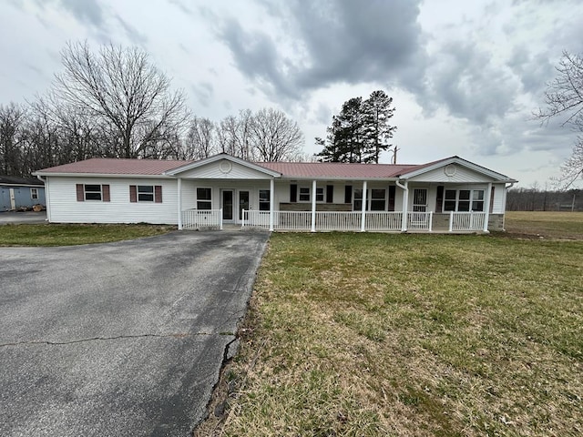 single story home featuring aphalt driveway, a front yard, covered porch, and metal roof