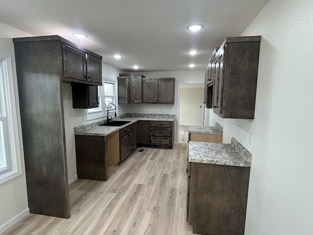 kitchen featuring baseboards, dark brown cabinetry, recessed lighting, light wood-style floors, and a sink