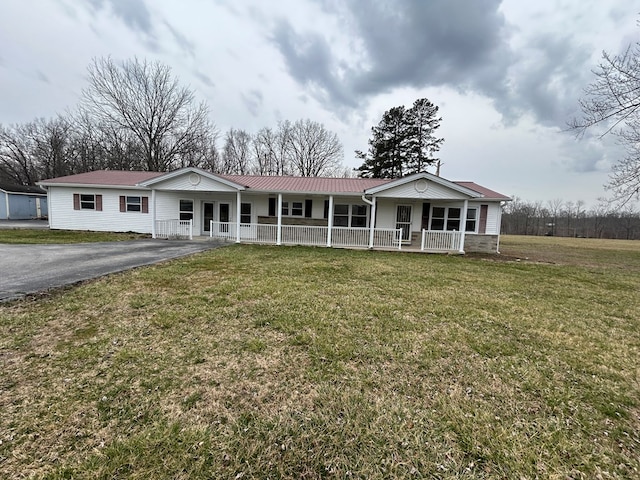 view of front of property with aphalt driveway, covered porch, metal roof, and a front lawn