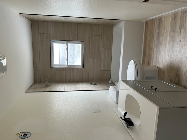 full bathroom featuring washer / dryer, wooden walls, walk in shower, and toilet