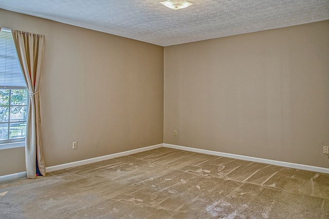 spare room with carpet floors, baseboards, and a textured ceiling