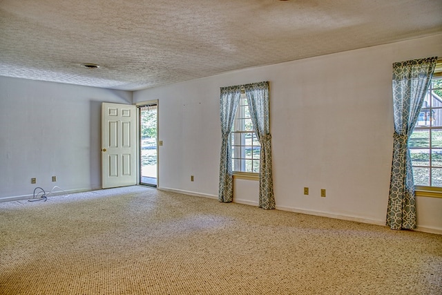 spare room with carpet, baseboards, and a textured ceiling