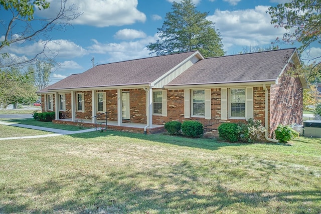 ranch-style house with covered porch, roof with shingles, a front yard, and brick siding