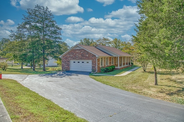 single story home with a garage, aphalt driveway, a front lawn, and brick siding