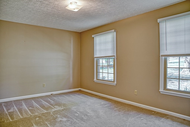 carpeted empty room with baseboards, a textured ceiling, and a healthy amount of sunlight