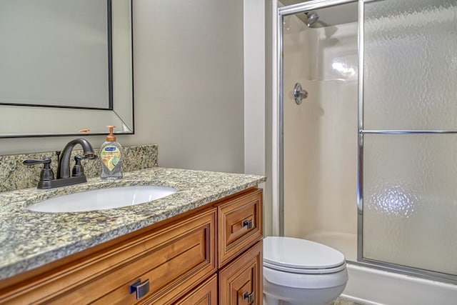 bathroom featuring a shower stall, toilet, and vanity