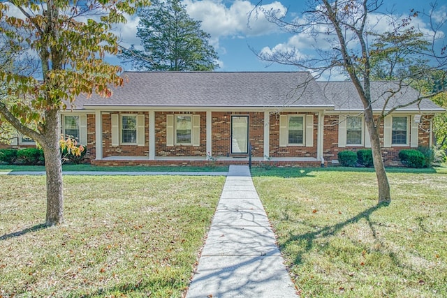 view of front of house with a front yard, brick siding, and roof with shingles