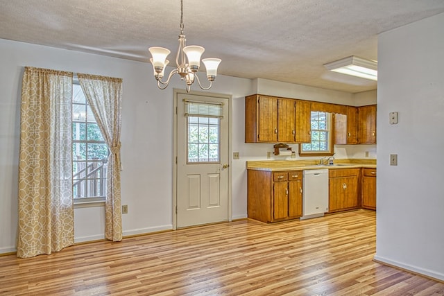 kitchen with brown cabinetry, light wood-style flooring, white dishwasher, light countertops, and a sink