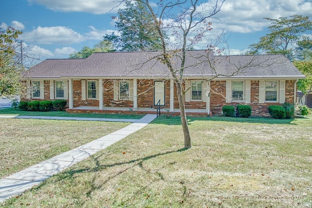 ranch-style house with a front lawn, roof with shingles, a porch, and brick siding