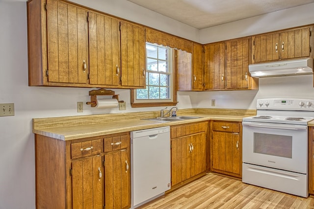 kitchen featuring white appliances, brown cabinets, light countertops, under cabinet range hood, and a sink