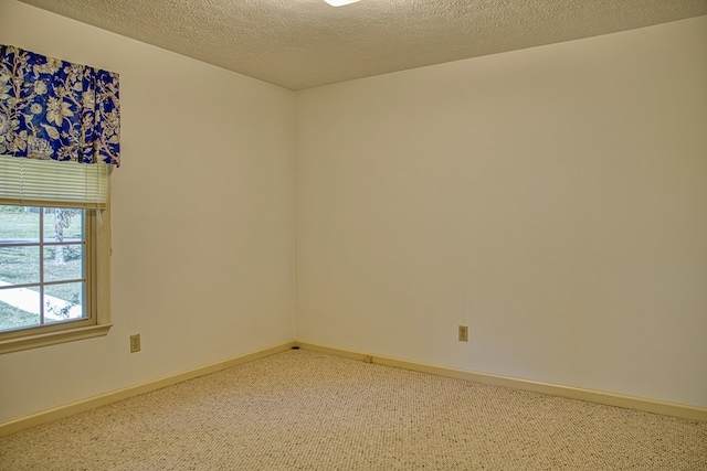 carpeted spare room featuring a textured ceiling and baseboards