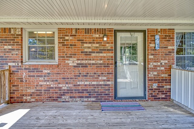 entrance to property featuring a deck and brick siding