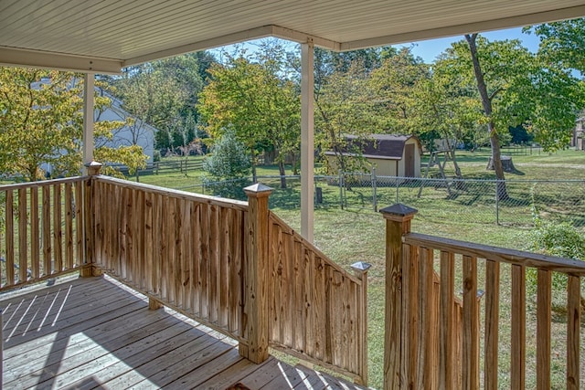 deck with a fenced backyard, an outbuilding, and a yard