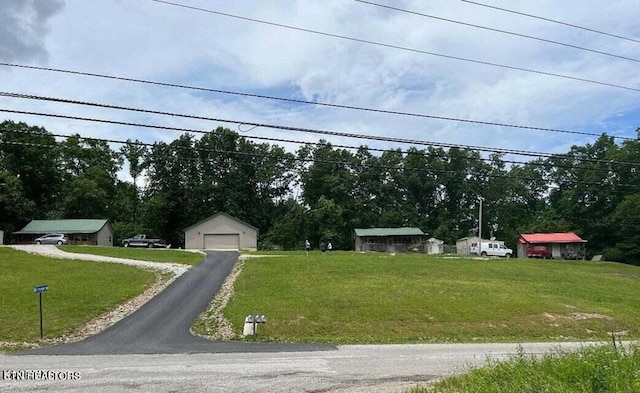 view of yard with a detached garage, driveway, and an outdoor structure