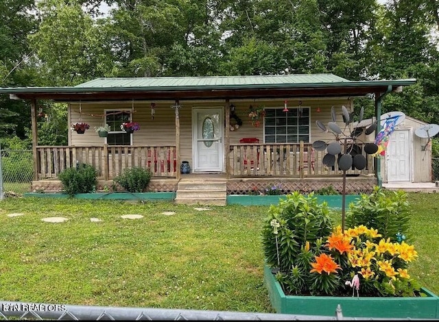 view of front of property featuring covered porch, metal roof, and a front lawn