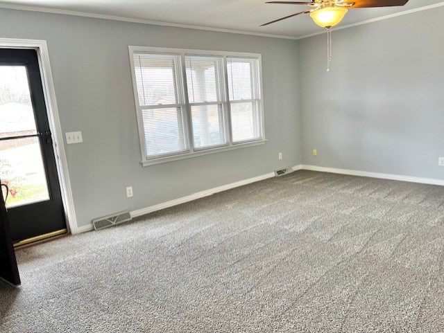 spare room with baseboards, carpet, visible vents, and crown molding