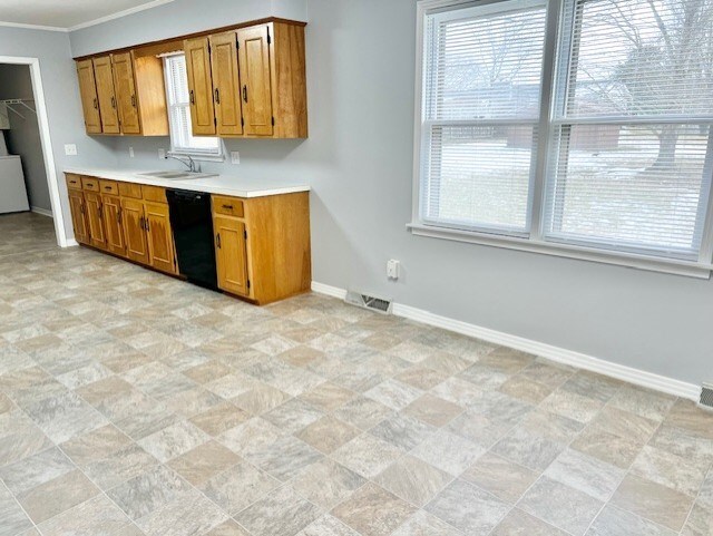 kitchen featuring light countertops, visible vents, brown cabinetry, a sink, and dishwasher