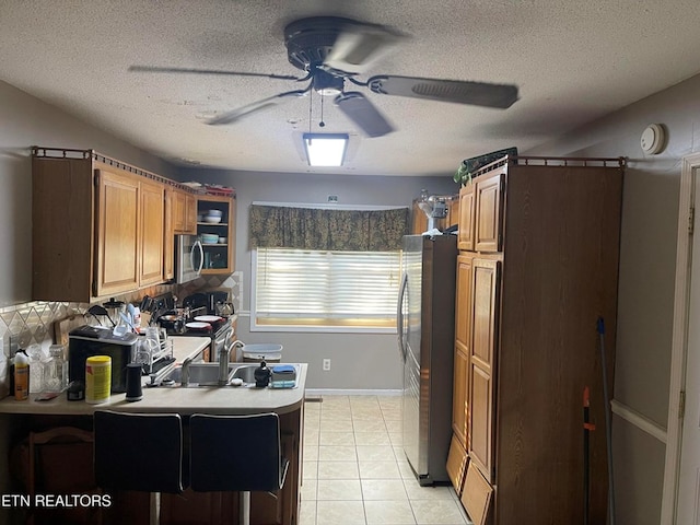 kitchen featuring a breakfast bar, brown cabinets, light tile patterned floors, light countertops, and appliances with stainless steel finishes