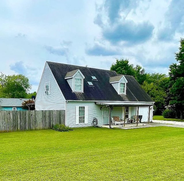 back of property with fence, a lawn, a garage, driveway, and a patio
