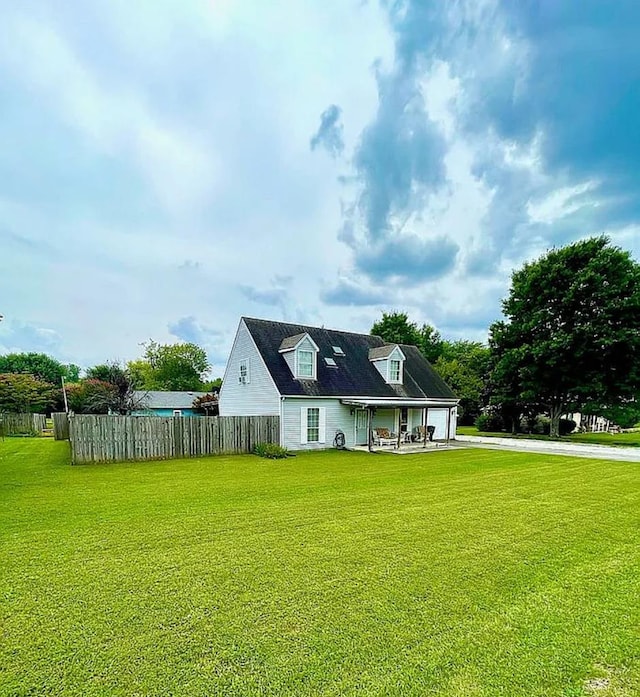 rear view of property featuring concrete driveway, a yard, fence, and a garage