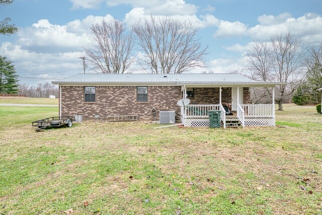 view of front of house featuring brick siding, metal roof, covered porch, cooling unit, and a front yard