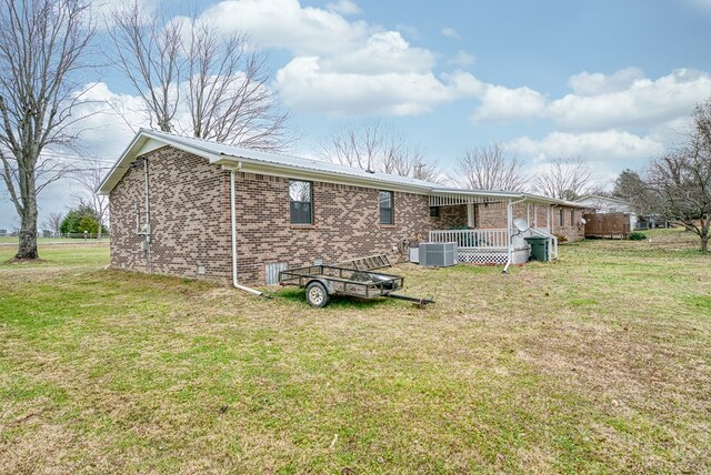 back of house with a yard, metal roof, cooling unit, and brick siding