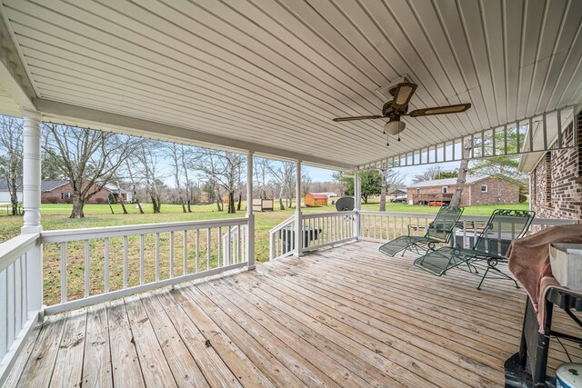 wooden deck featuring a residential view, a ceiling fan, a lawn, and outdoor dining space