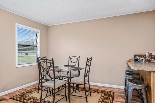 dining room featuring baseboards, visible vents, wood finished floors, crown molding, and a textured ceiling