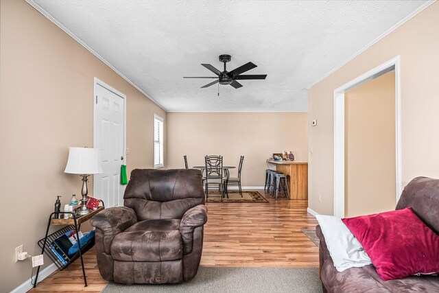 living area featuring ornamental molding, a ceiling fan, a textured ceiling, and wood finished floors