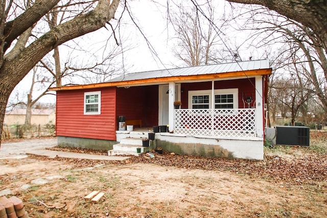 view of front facade with covered porch, central AC unit, and metal roof