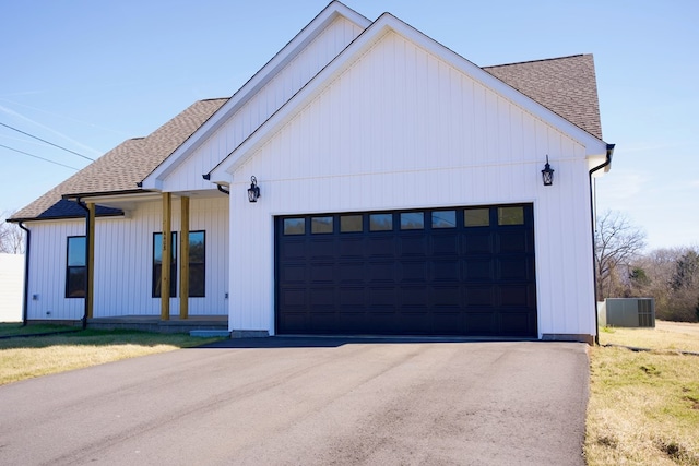 modern inspired farmhouse featuring a garage, driveway, and roof with shingles