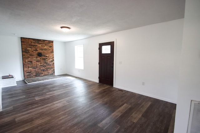 entryway featuring dark wood-type flooring, visible vents, a textured ceiling, and baseboards