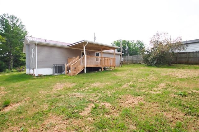 back of house featuring a lawn, a fenced backyard, metal roof, stairs, and a wooden deck