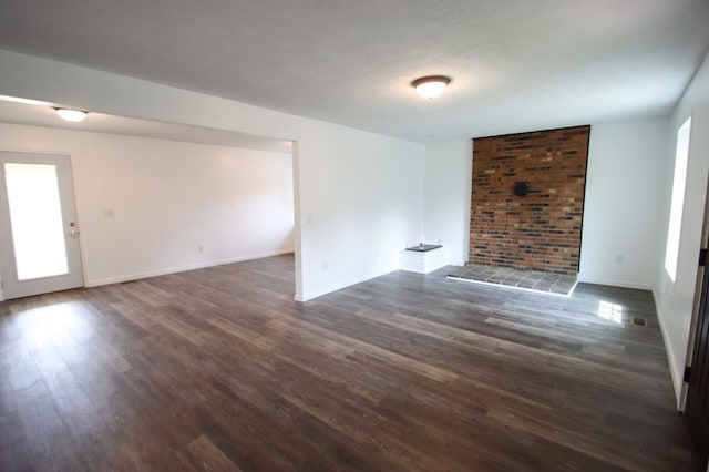 unfurnished living room featuring dark wood-style floors, a textured ceiling, and baseboards