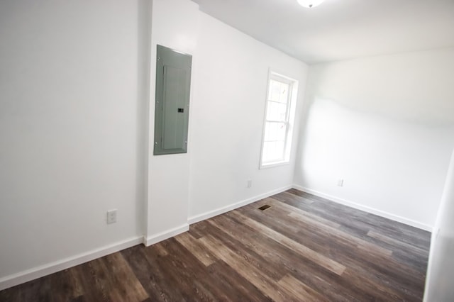 unfurnished room with dark wood finished floors, electric panel, and baseboards