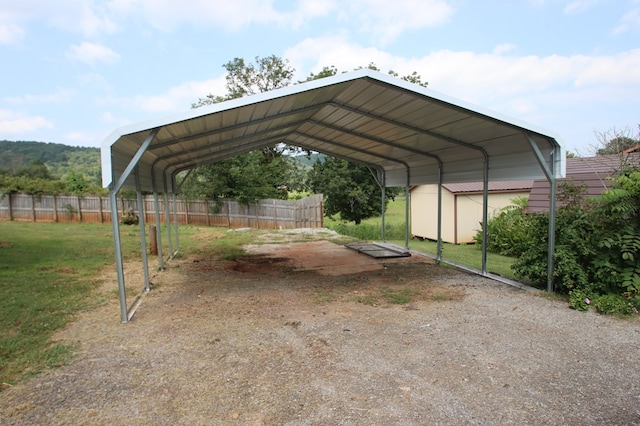 view of parking / parking lot featuring a storage shed, fence, and a detached carport