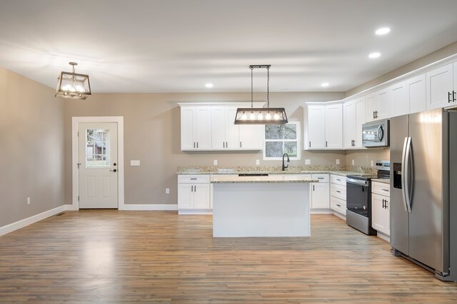 kitchen with white cabinets, appliances with stainless steel finishes, and pendant lighting