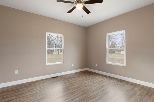 empty room featuring a ceiling fan, visible vents, baseboards, and wood finished floors