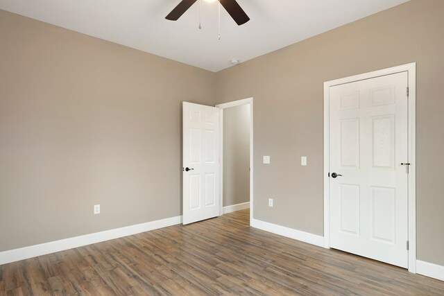 unfurnished bedroom featuring dark wood finished floors, a ceiling fan, and baseboards