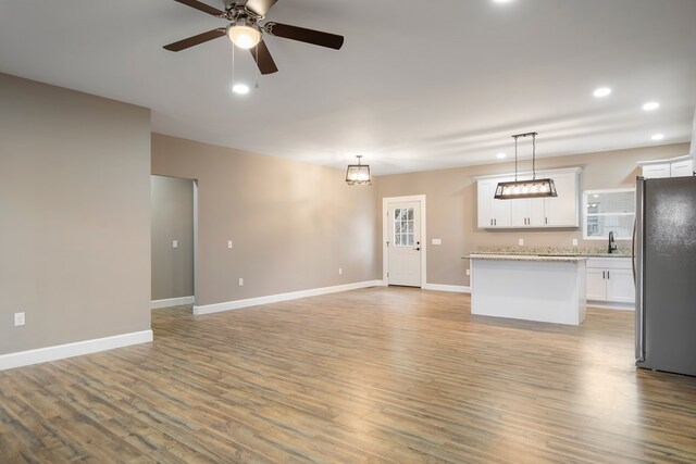 interior space featuring open floor plan, white cabinets, freestanding refrigerator, and decorative light fixtures