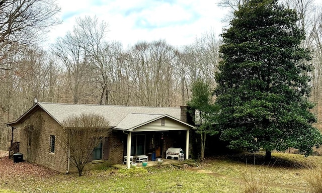 rear view of property with central AC, brick siding, roof with shingles, and a chimney