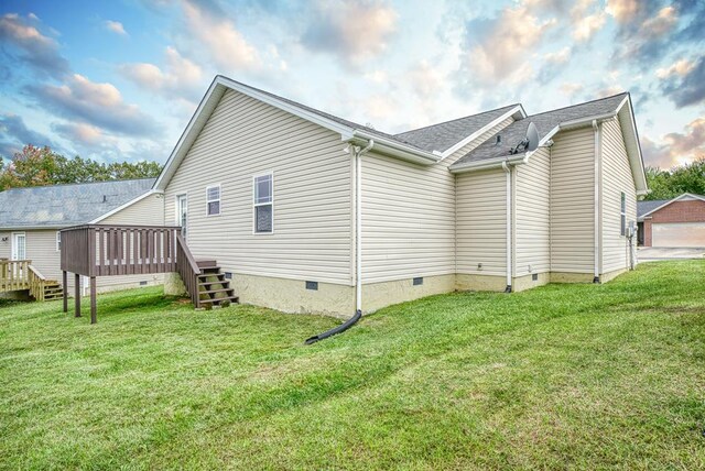 view of side of home with roof with shingles, crawl space, stairs, a deck, and a yard