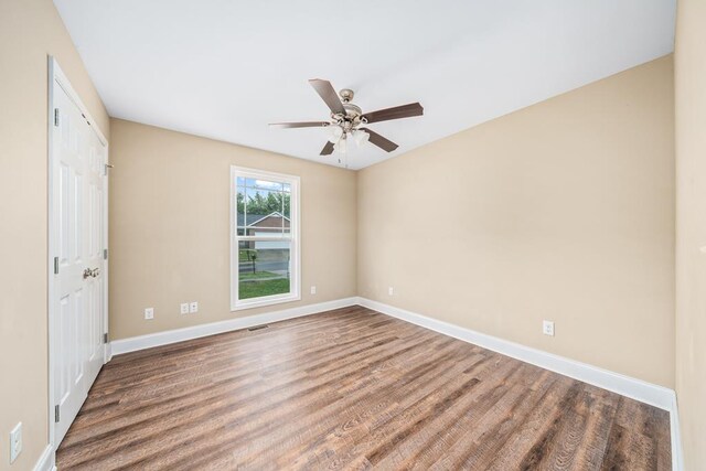 unfurnished bedroom with a closet, visible vents, ceiling fan, wood finished floors, and baseboards