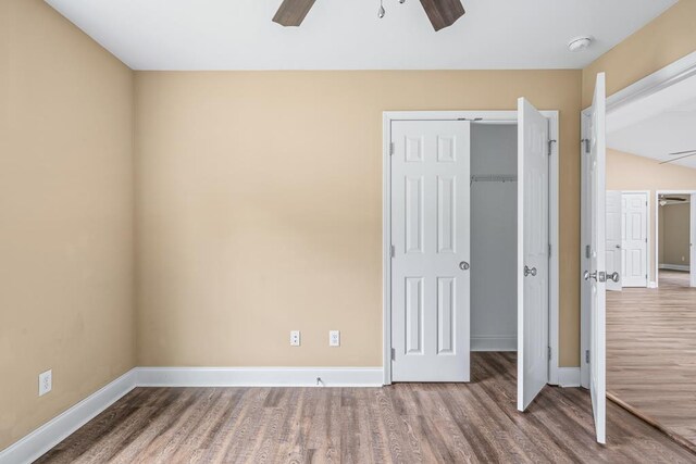 unfurnished bedroom with a ceiling fan, a closet, baseboards, and wood finished floors