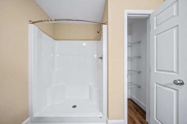 bathroom featuring baseboards, a shower, and wood finished floors