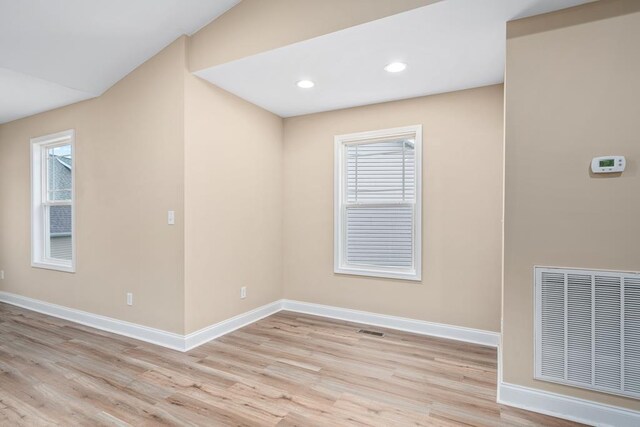 empty room featuring light wood finished floors, plenty of natural light, visible vents, and baseboards