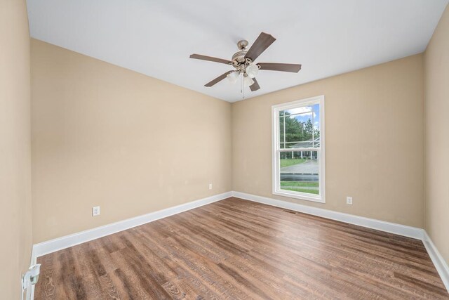 unfurnished room with ceiling fan, visible vents, baseboards, and wood finished floors